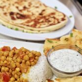 Flavorful Chickpea Curry Feast: Spice Up Your Mealtime with Naan Bread and Refreshing Cucumber Raita