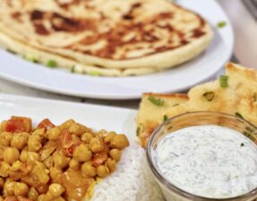 Flavorful Chickpea Curry Feast: Spice Up Your Mealtime with Naan Bread and Refreshing Cucumber Raita